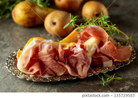 Prosciutto with pears and thyme on a silver tray. Prosciutto with pears and thyme on a silver tray. 135729583