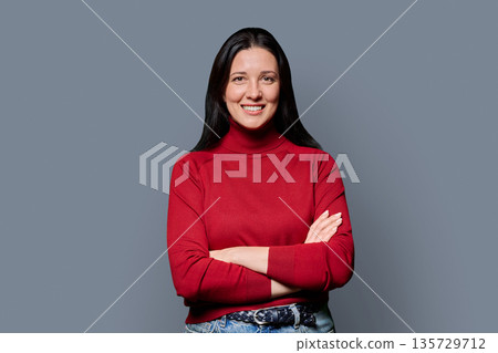 Portrait of beautiful smiling 40 years old woman posing on grey background Portrait of beautiful smiling 40 years old woman posing on grey background 135729712