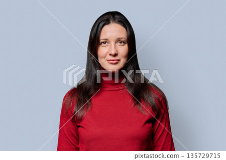 Portrait of beautiful smiling 40 years old woman posing on light gray background Portrait of beautiful smiling 40 years old woman posing on light gray background 135729715