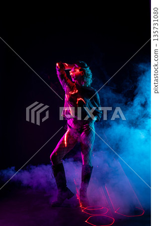 Futuristic woman in LED glasses dancing in neon lights with laser beams and smoke Futuristic woman in LED glasses dancing in neon lights with laser beams and smoke 135731080