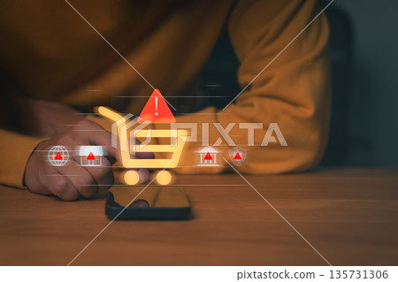 Person using smartphone with digital shopping cart and warning icons, symbolizing online shopping fraud, e-commerce scam, and payment risk. Concept of cybersecurity and consumer protection awareness. 135731306