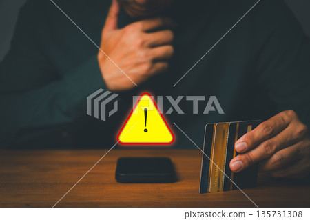 Person holding credit cards near smartphone with warning sign, symbolizing online payment fraud, credit card scam, and financial security risk. Concept of cybercrime prevention and digital safety. Person holding credit cards near smartphone with warning sign, symbolizing online payment fraud, credit card scam, and financial security risk. Concept of cybercrime prevention and digital safety. 135731308