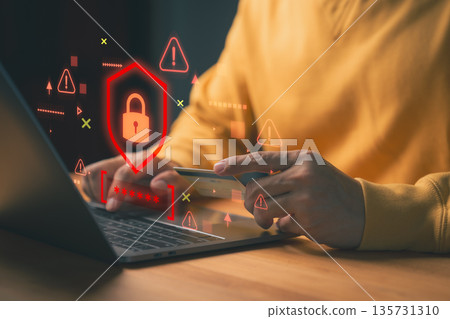 Person holding a credit card while using laptop, with red warning symbols and a digital padlock, representing online payment fraud, scam, cybersecurity threats, data breaches, and identity theft risk. Person holding a credit card while using laptop, with red warning symbols and a digital padlock, representing online payment fraud, scam, cybersecurity threats, data breaches, and identity theft risk. 135731310