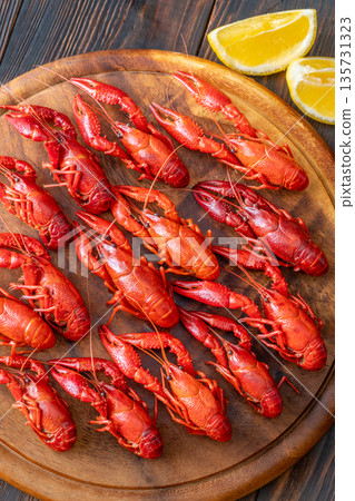 Top down boiled crawfish arranged on wooden board with lemon wedges, rustic background Top down boiled crawfish arranged on wooden board with lemon wedges, rustic background 135731323