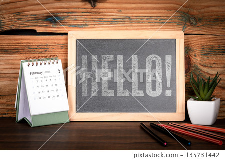 HELLO. Chalkboard Message With Desk Calendar February 2026 On Wooden Workspace HELLO. Chalkboard Message With Desk Calendar February 2026 On Wooden Workspace 135731442