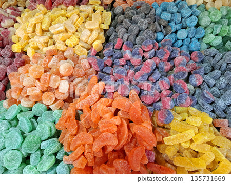A collection of handmade marmalade pieces is arranged in a colorful display at an outdoor market. Vendors showcase different flavors and textures under the warm light of the afternoon. A collection of handmade marmalade pieces is arranged in a colorful display at an outdoor market. Vendors showcase different flavors and textures under the warm light of the afternoon. 135731669