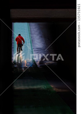 一名男子騎著自行車穿過地下通道。 一名男子騎著自行車穿過地下通道。 135731921