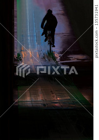 A man riding his bicycle through an illuminated underpass tunnel on a rainy day A man riding his bicycle through an illuminated underpass tunnel on a rainy day 135731941