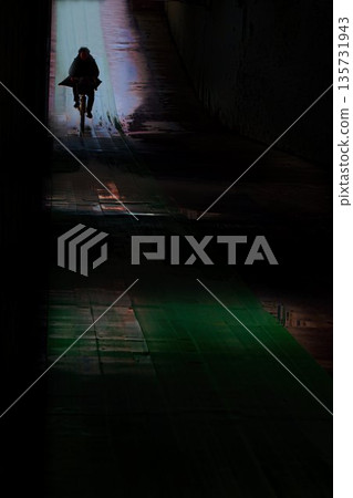 夜裡,一名男子騎著自行車穿過地下通道。 夜裡,一名男子騎著自行車穿過地下通道。 135731943