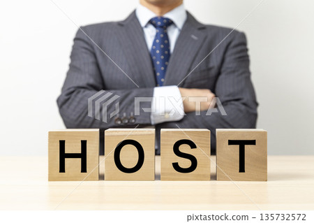 一位商人雙手交叉在胸前，手裡拿著一塊寫著「HOST」字樣的積木。 135732572
