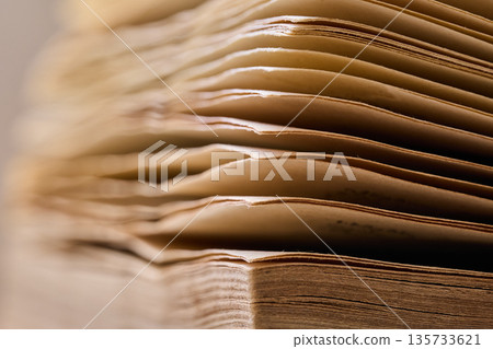 Detailed view of aged paper layers and book binding with soft focus and warm lighting 135733621