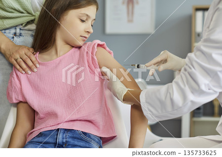 Pediatric clinic vaccination: doctor gives child an injection while parent helps 135733625