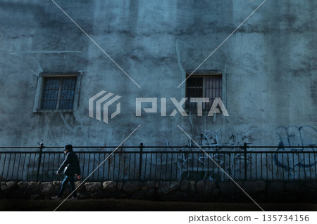 People passing by in front of an abandoned building 135734156