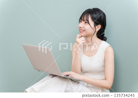 Young Asian woman smiling and thinking using a computer at home (fun, imagination, conception, planning, plan) Young Asian woman smiling and thinking using a computer at home (fun, imagination, conception, planning, plan) 135734245
