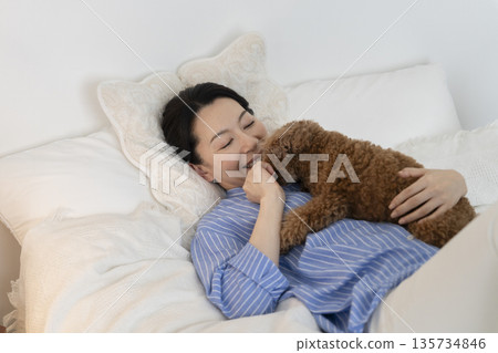 一位中年婦女躺在床上，抱著她的寵物狗。 135734846