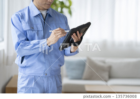 一個穿著工作服的男人的手正在平板電腦上打字 135736008