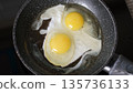 Cracking fresh eggs frying in a hot pan, top view. Morning cooking and breakfast preparation concept  135736133