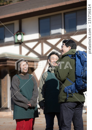 一對夫婦和徒步旅行者正在鄉村一家家庭經營的旅館為客人和接待員提供嚮導服務。 135736814