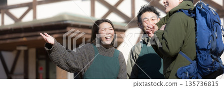 一對夫婦和徒步旅行者正在鄉村一家家庭經營的旅館為客人和接待員提供嚮導服務。 一對夫婦和徒步旅行者正在鄉村一家家庭經營的旅館為客人和接待員提供嚮導服務。 135736815