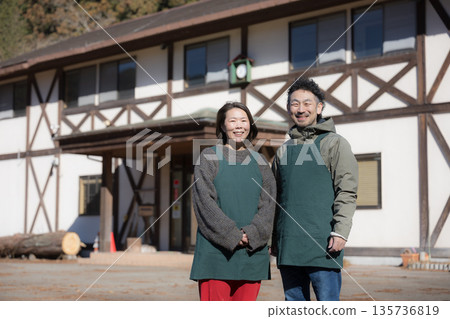 Image of a couple running a family-run inn, pension, and cafe in the countryside, looking at the camera Image of a couple running a family-run inn, pension, and cafe in the countryside, looking at the camera 135736819