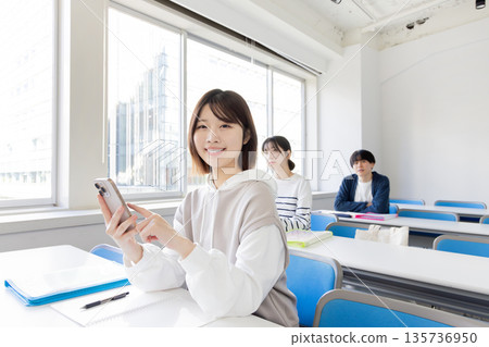 大學生在教室裡看智慧型手機 大學生在教室裡看智慧型手機 135736950
