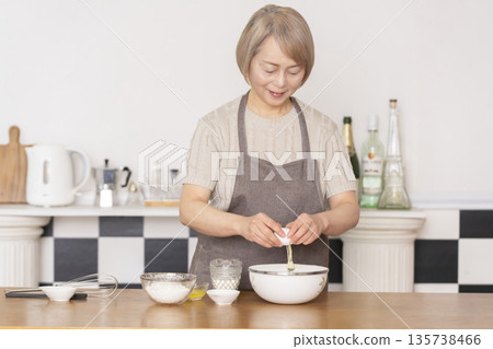 一位老婦人在廚房裡烤美式華夫餅 一位老婦人在廚房裡烤美式華夫餅 135738466