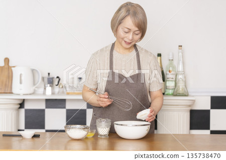 一位老婦人在廚房裡烤美式華夫餅 135738470