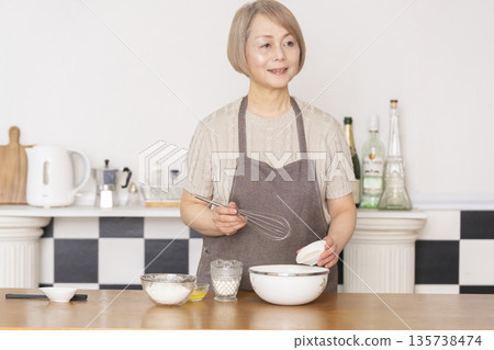 Senior woman baking American waffles in the kitchen Senior woman baking American waffles in the kitchen 135738474