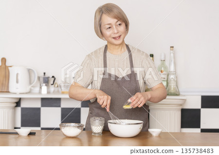 一位老婦人在廚房裡烤美式華夫餅 一位老婦人在廚房裡烤美式華夫餅 135738483