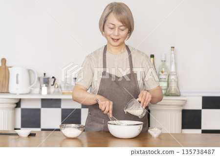 Senior woman baking American waffles in the kitchen Senior woman baking American waffles in the kitchen 135738487