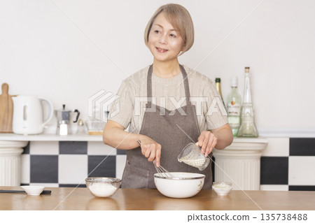 Senior woman baking American waffles in the kitchen Senior woman baking American waffles in the kitchen 135738488