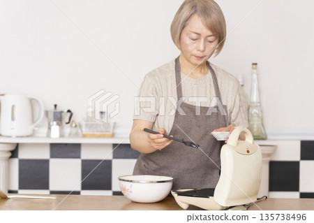 Senior woman baking American waffles in the kitchen Senior woman baking American waffles in the kitchen 135738496