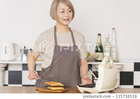 一位老婦人在廚房裡烤美式華夫餅 135738519