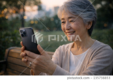 黃昏時分,日本老人們在公園使用智慧型手機。 黃昏時分,日本老人們在公園使用智慧型手機。 135738853