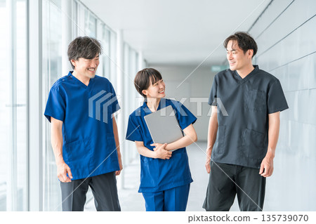 身穿手術服的男女醫護人員正走在醫院走廊上。 身穿手術服的男女醫護人員正走在醫院走廊上。 135739070