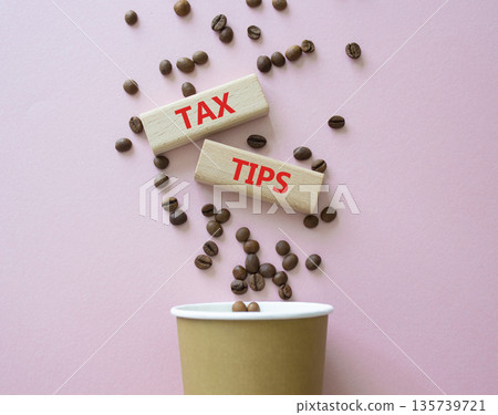 Tax Tips symbol. Wooden blocks with words Tax Tips. Beautiful pink background with coffee cup and coffee beans. Business and Tax Tips concept. Copy space. 135739721