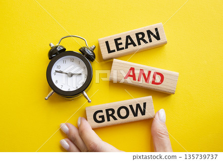Learn and grow symbol. Concept words Learn and grow on wooden blocks. Businessman hand. Beautiful yellow background with alarm clock. Business and Learn and grow concept. Copy space. Learn and grow symbol. Concept words Learn and grow on wooden blocks. Businessman hand. Beautiful yellow background with alarm clock. Business and Learn and grow concept. Copy space. 135739737
