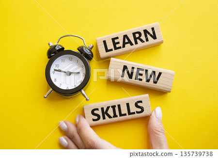 Learn new skills symbol. Concept words Learn new skills on wooden blocks. Businessman hand. Beautiful yellow background with alarm clock. Business and Learn new skills concept. Copy space. Learn new skills symbol. Concept words Learn new skills on wooden blocks. Businessman hand. Beautiful yellow background with alarm clock. Business and Learn new skills concept. Copy space. 135739738