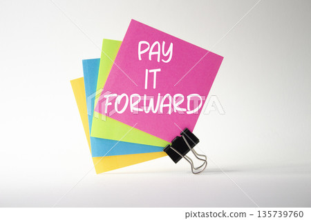 Pay it forward symbol. Concept words Pay it forward on pink sticky note with paper clips. Beautiful white background. Business and Pay it forward concept. Copy space. Pay it forward symbol. Concept words Pay it forward on pink sticky note with paper clips. Beautiful white background. Business and Pay it forward concept. Copy space. 135739760