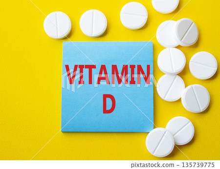 Vitamin D symbol. Concept word Vitamin D on blue note. Beautiful yellow background with pills. Medicine and Vitamin D concept. Copy space 135739775