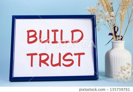 Build trust symbol. Concept words Build trust on beautiful wooden picture frame. Beautiful light blue background with flower vase. Business and Build trust concept. Copy space. Build trust symbol. Concept words Build trust on beautiful wooden picture frame. Beautiful light blue background with flower vase. Business and Build trust concept. Copy space. 135739781