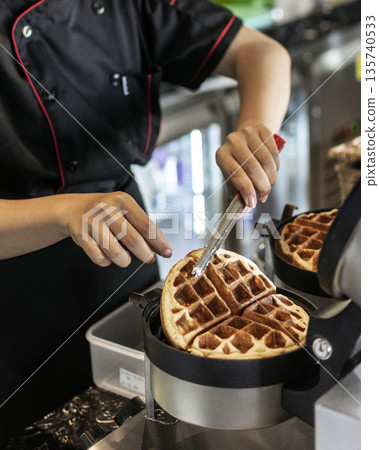 cafe worker making belgian waffles with professional machine 135740533