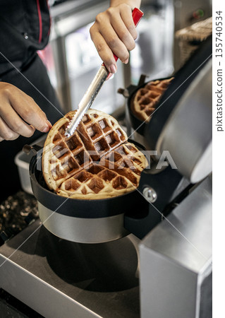 cafe worker making belgian waffles with professional machine 135740534