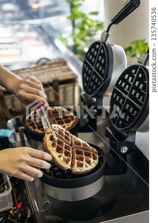 cafe worker making belgian waffles with professional machine cafe worker making belgian waffles with professional machine 135740536