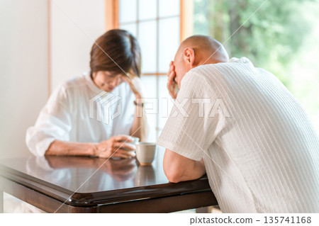 Senior couple holding their heads in shock in a Japanese-style room at home (depressed, serious, trouble) Senior couple holding their heads in shock in a Japanese-style room at home (depressed, serious, trouble) 135741168