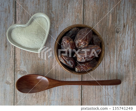 Dried Dates in Wooden Bowl with Spoon and Cane Sugar Heart on Rustic Table 135741249
