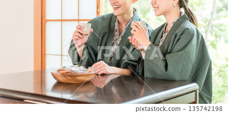 A couple in yukata drinking tea in a Japanese-style room at a ryokan with a garden view A couple in yukata drinking tea in a Japanese-style room at a ryokan with a garden view 135742198
