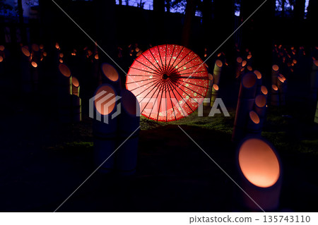Bright red Japanese umbrellas and lit bamboo lanterns floating in the darkness 135743110