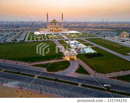 Aerial View of Sharjah Mosque at Sunset Showcasing Symmetrical Islamic Architecture Aerial View of Sharjah Mosque at Sunset Showcasing Symmetrical Islamic Architecture 135744250