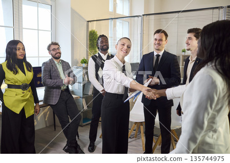 Diverse business team meeting with handshake and applause in modern office Diverse business team meeting with handshake and applause in modern office 135744975